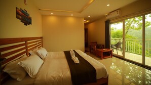 A hotel room with a large bed, a balcony with a view, and a small seating area. - Mizzle Resort (Vythiri)