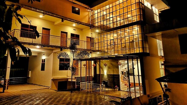 A multi-story building with a balcony on the upper floor, a staircase leading to the upper level, and a covered outdoor area with a patterned floor. - Mizzle Resort (Vythiri)