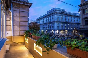 Ein Balkon mit Blumentöpfen und Blick auf ein klassizistisches Gebäude.