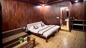 A bedroom with a wooden ceiling, a bed with a white and brown bedspread, a wooden floor, and a small table with a plant. - Camp Mountain Valley (Dhanaulti)