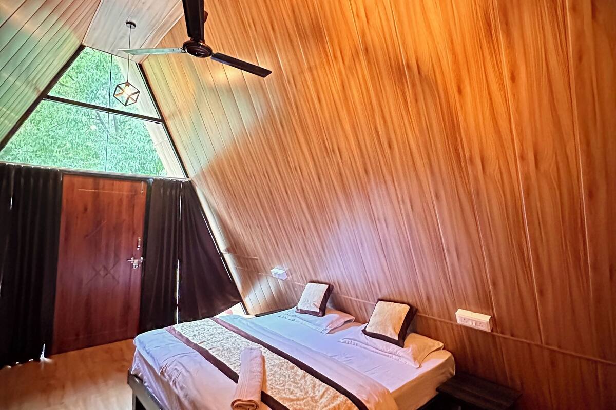 Una habitación acogedora con techo inclinado, una cama, paredes de madera y un ventilador de techo.