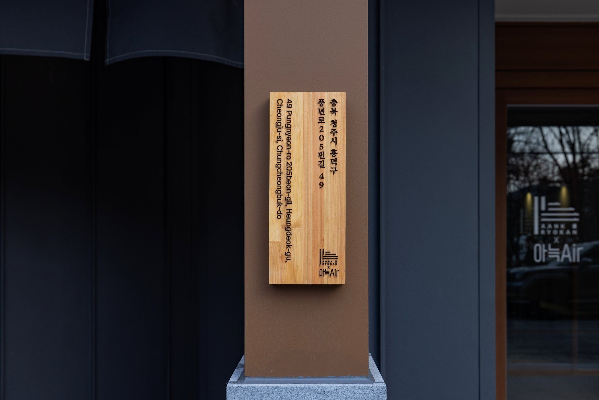 A wooden plaque with text on a building's exterior wall.