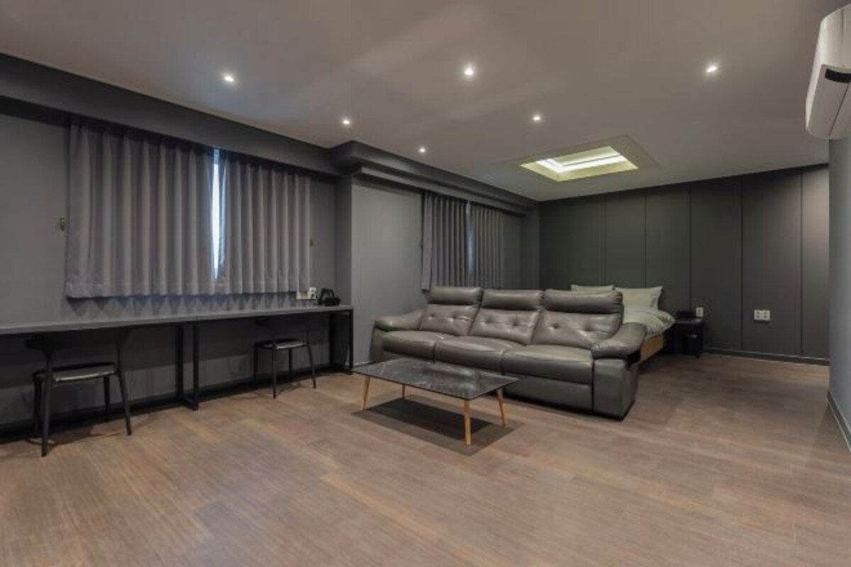 A modern living room with a leather sofa, a glass coffee table, and a dining area with a long table and chairs.