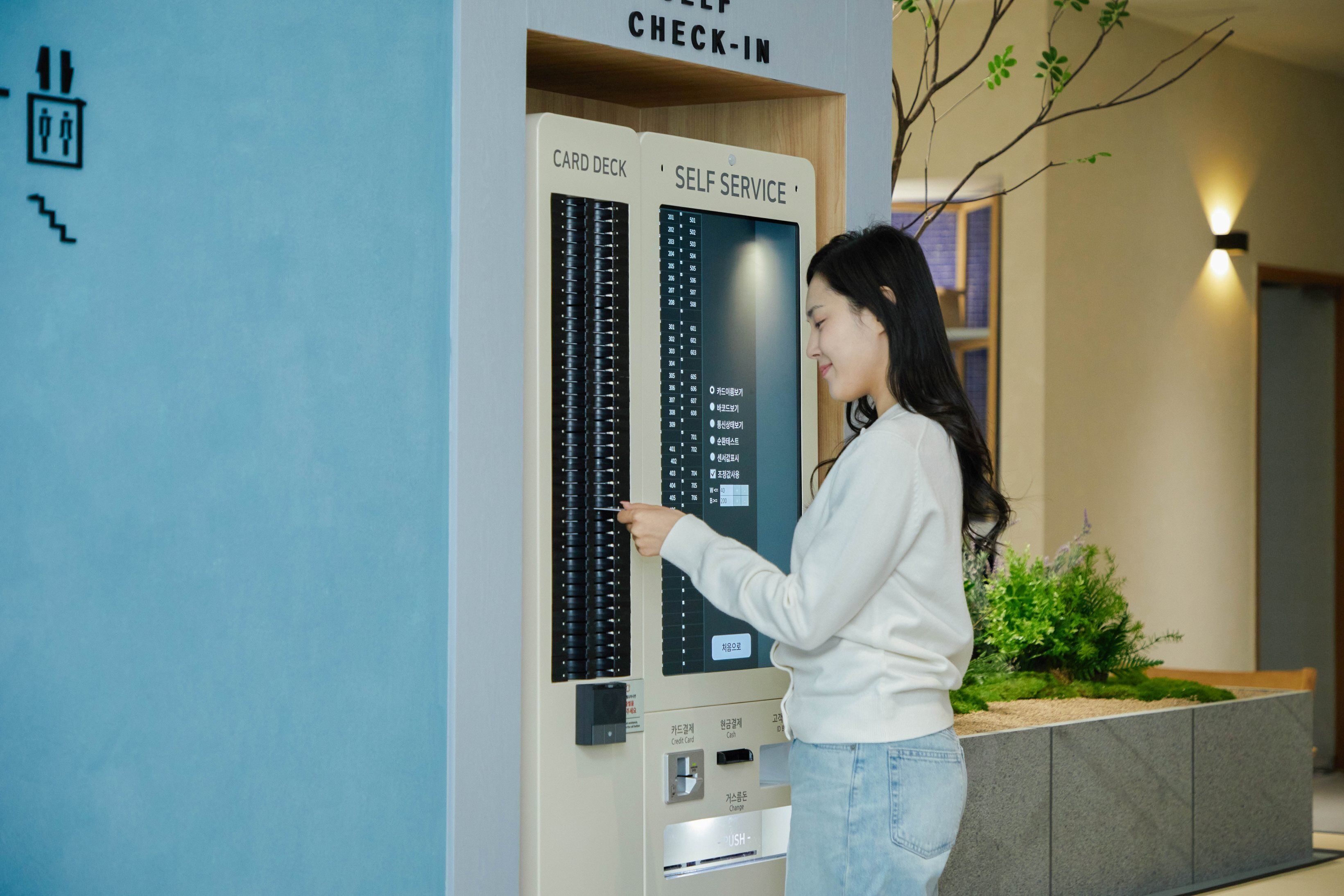 A woman interacting with a self-service card deck in a hotel lobby.