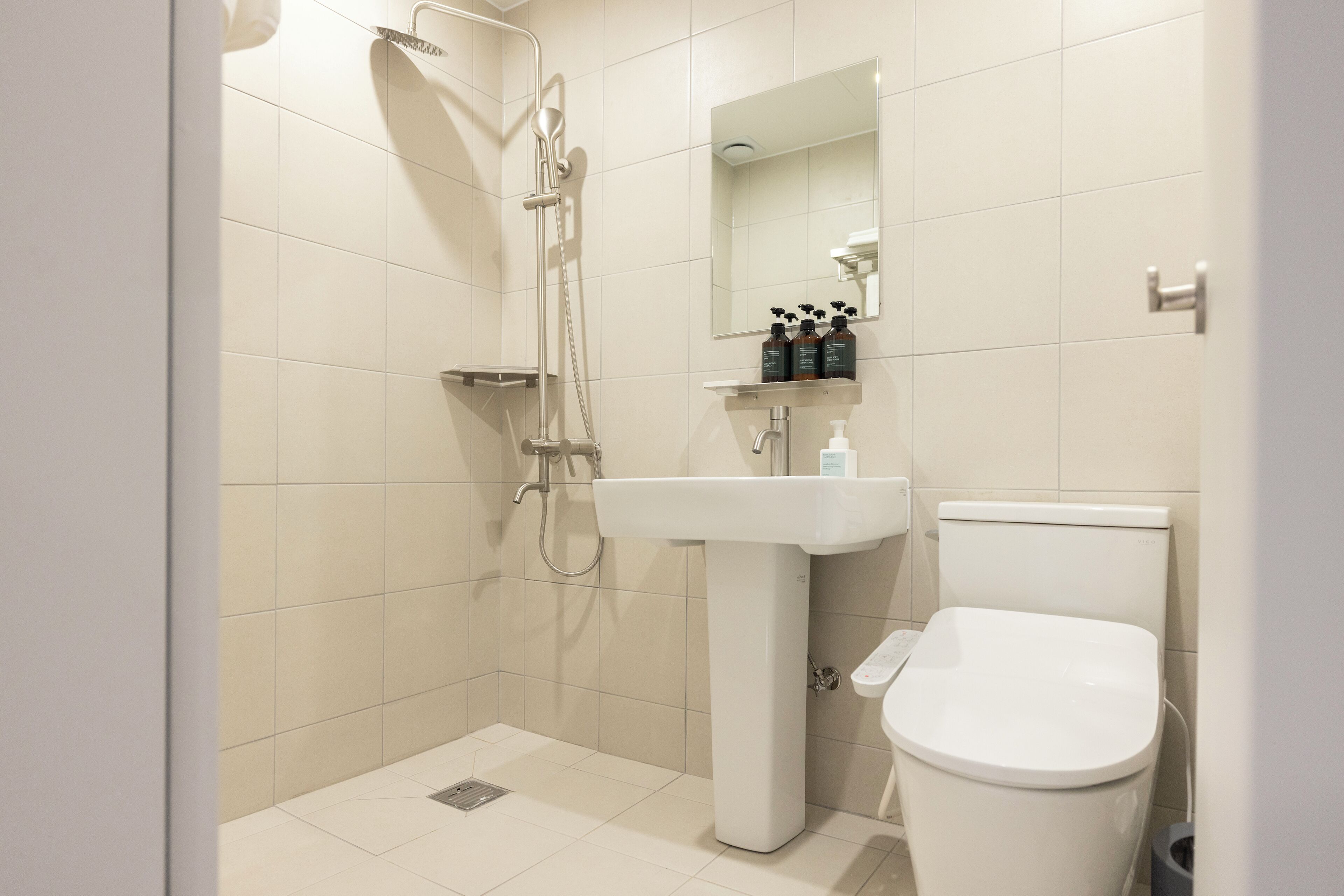 A modern bathroom with a shower, sink, and toilet.