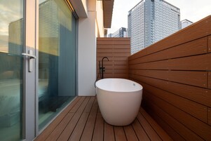 Un baño moderno con una bañera grande, paneles de pared de madera y una mampara de cristal.