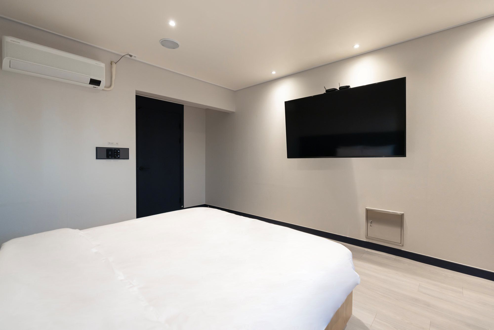 Une chambre moderne équipée d’un lit, d’un téléviseur fixé au mur et d’un appareil de climatisation.