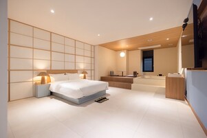 Un dormitorio moderno con una cama grande, mesitas de noche, un escritorio y un banco empotrado.