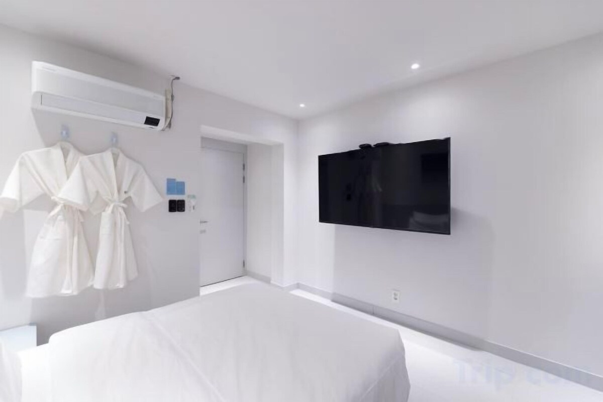 Habitación de hotel con cama, televisor en la pared y perchero.