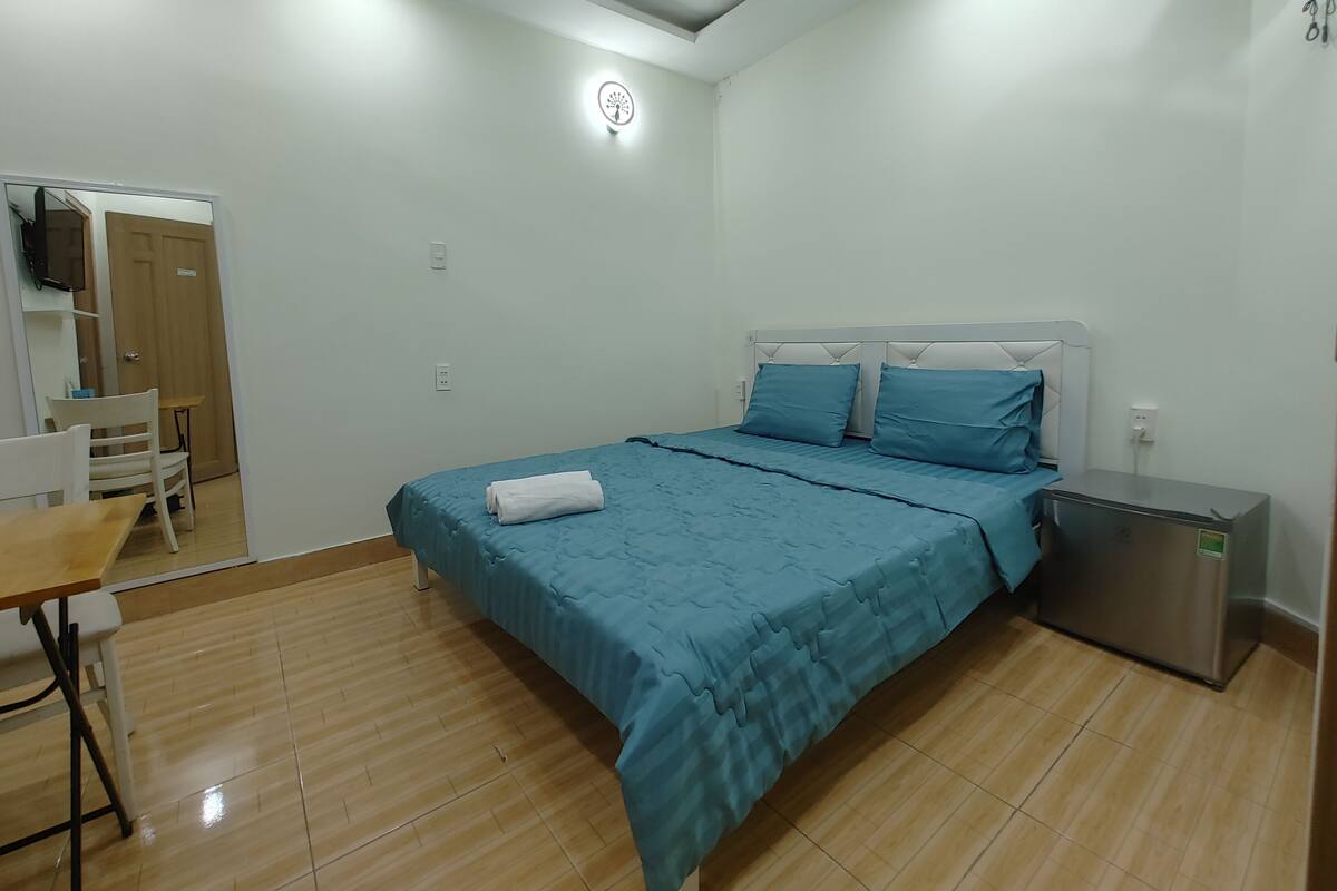 A bedroom with a bed, a desk, and a chair.