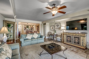 A living room with a sofa, coffee table, TV, and a ceiling fan.