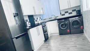 Uma cozinha moderna com eletrodomésticos de aço inoxidável, máquina de lavar embutida e backsplash com padrão herringbone.