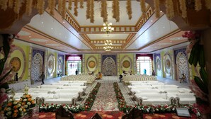 A grand hall with rows of white sofas, a central aisle, and ornate wall decorations.