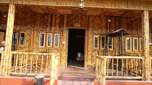 A bamboo-themed building with a wooden entrance, a sign above the door, and a staircase leading inside.