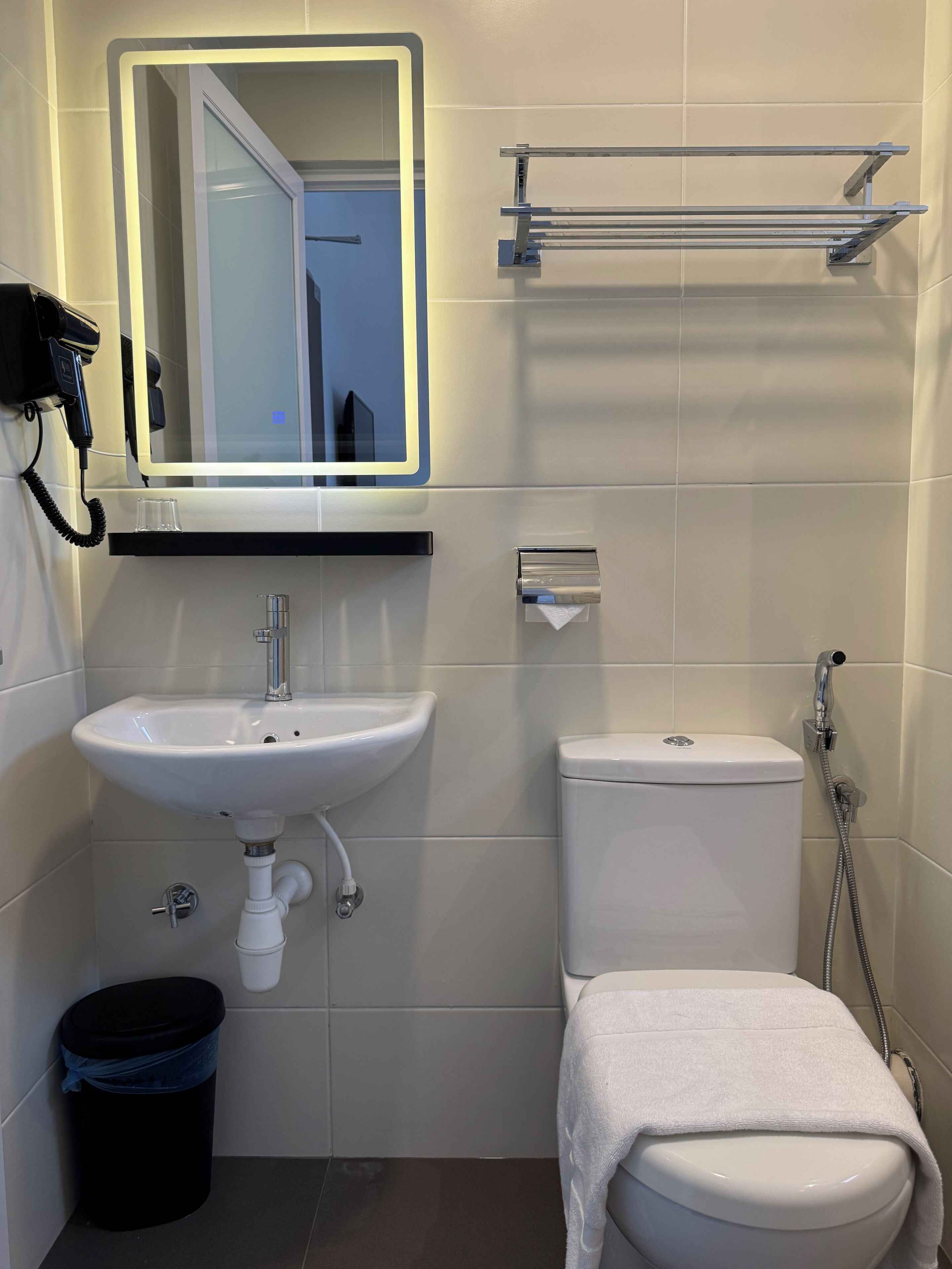 A bathroom with a white sink, toilet, and a towel rack.