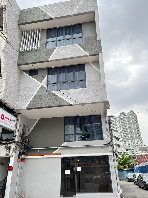 A multi-story building with a geometric facade, large windows with curtains, and a visible sign for 'Spectra Travel & Tours'. - Maca Hotel by Sky Hive (George Town)