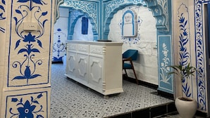 Ein Zimmer mit einer weißen Rezeption, Wänden mit blau-weißen Mustern und einem Fliesenboden.