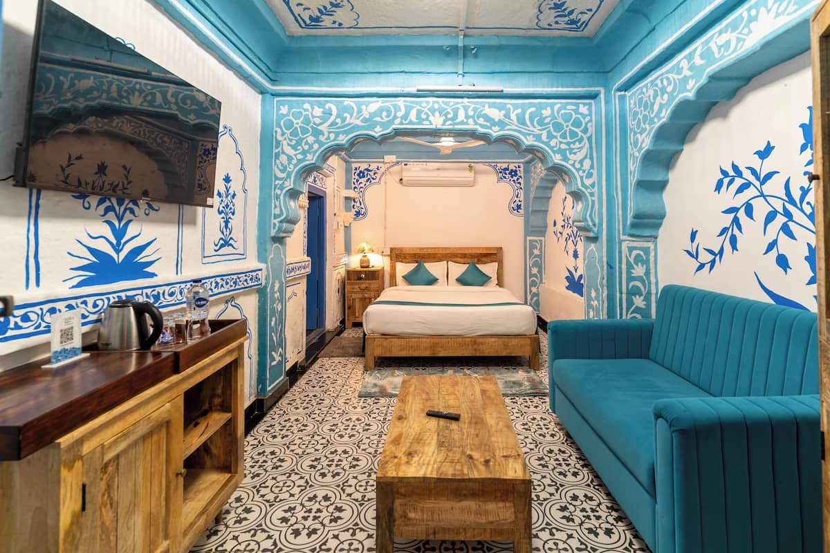 Ein Zimmer mit einem Bett, einem blauen Sofa, einem Holztisch und einem Schrank.