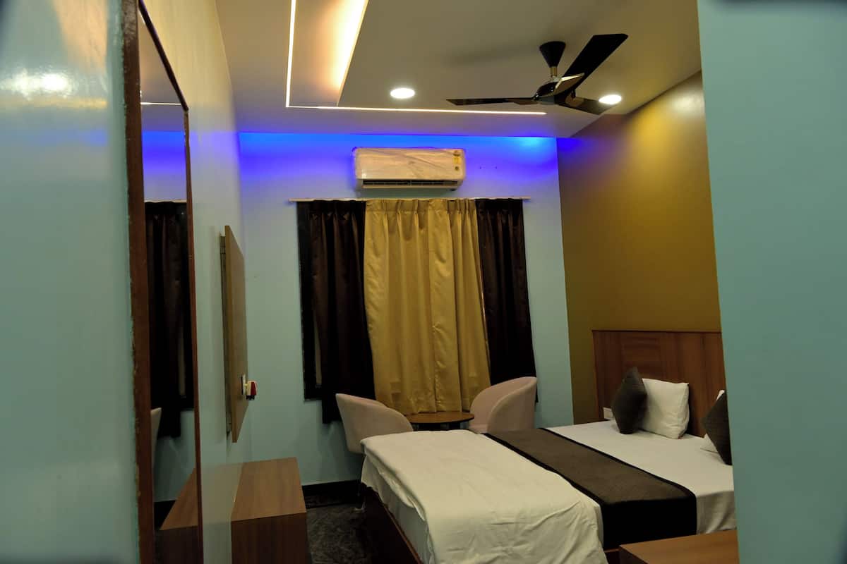 A hotel room with a bed, a desk, a chair, an air conditioning unit, and a ceiling fan.
