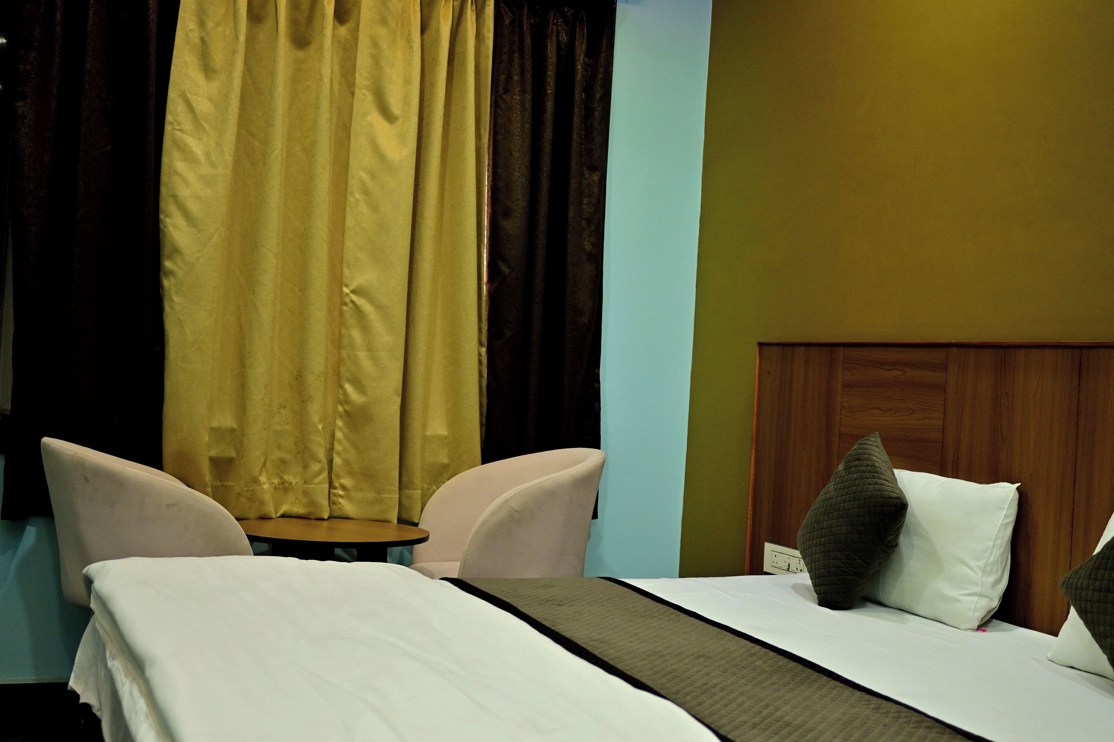 A hotel room with a bed, two chairs, a small table, and a wooden headboard.