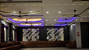 Un vestíbulo amplio con una zona de estar curvada, ventiladores de techo, iluminación empotrada y arte mural de mármol.