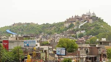 A hilltop temple complex with multiple domes and spires, surrounded by dense urban buildings and greenery.