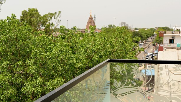 Vista de un templo con una aguja, rodeado de árboles verdes exuberantes y edificios al fondo.
