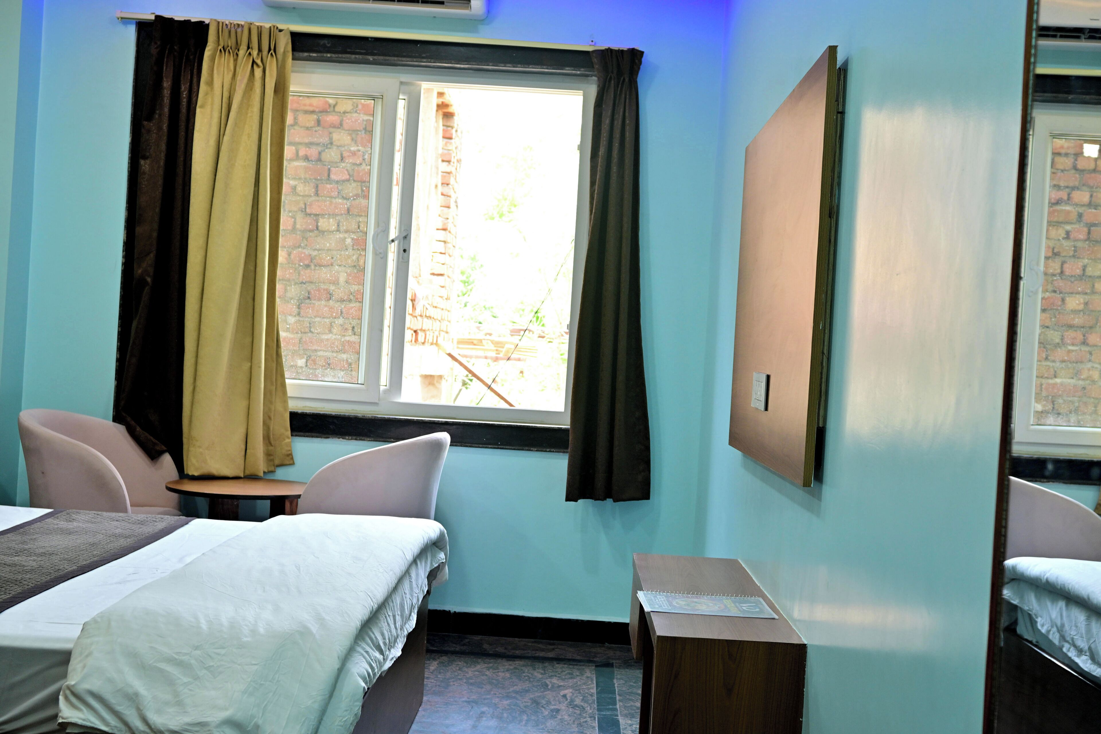 A room with two beds, a small table, and a window with curtains.