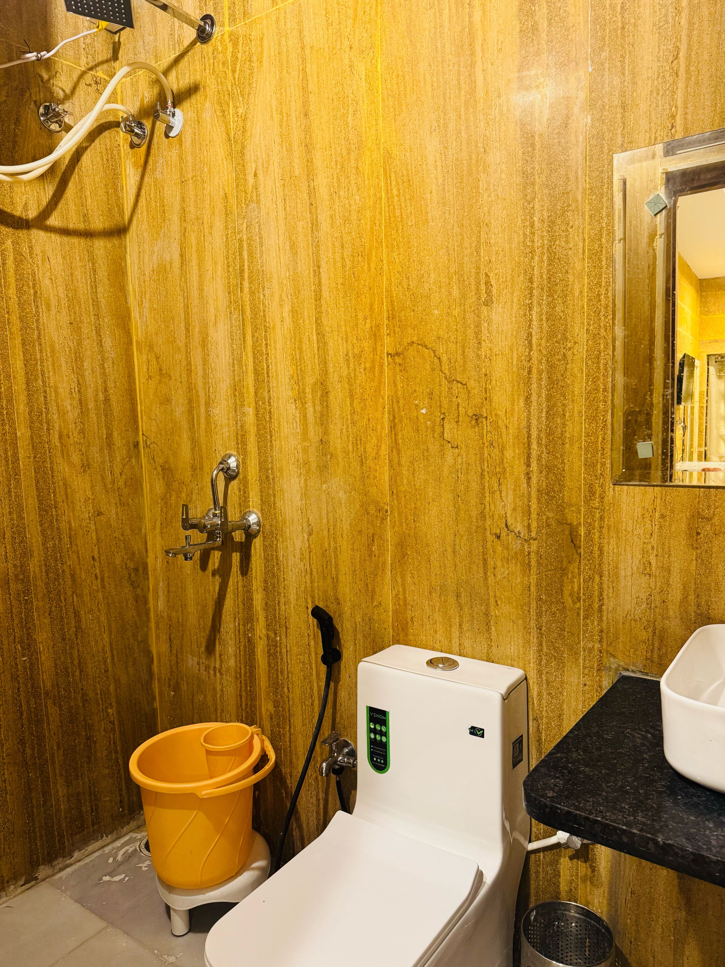A bathroom with a wooden wall, a toilet, a bidet, a sink, and a mirror.