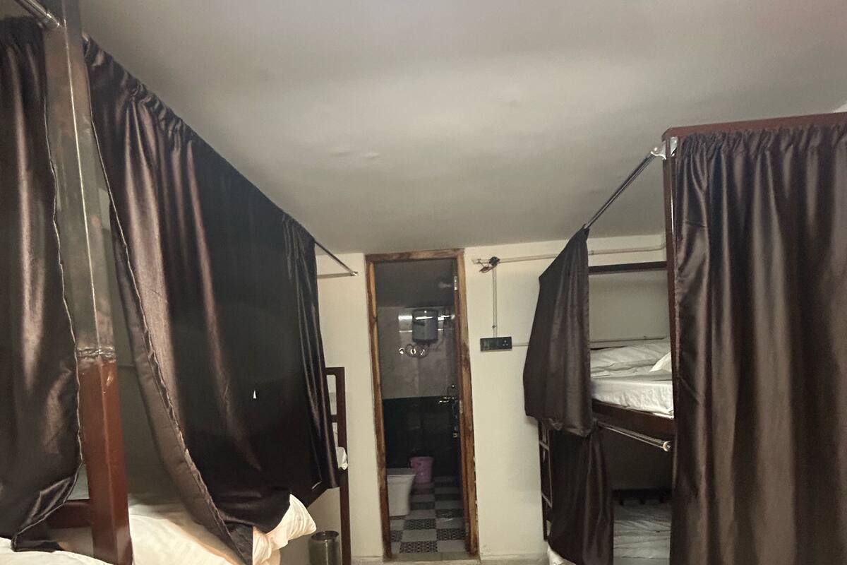 Een slaapzaal met twee stapelbedden, een kleine deur naar een badkamer en een betegelde vloer.