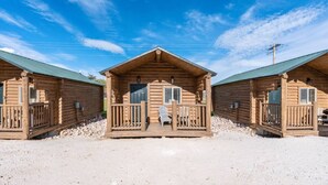 A row of log cabins with a porch and a chair in front.