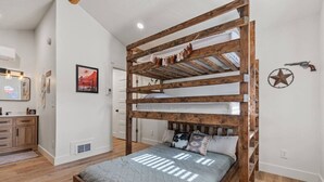 A bunk bed with a wooden frame, a gray quilted mattress, and a star decoration on the wall.