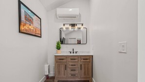 Un baño con tocador de madera, un espejo grande y un cuadro en la pared.