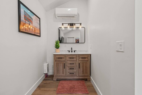 Un baño con tocador de madera, un espejo grande y un cuadro en la pared.