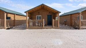 Une rangée de chalets en rondins, chacun doté d’un porche et d’une porte, construits sur un sol de gravier.