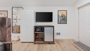 Un espace de vie compact comprenant un coin cuisine, un téléviseur à écran plat fixé au mur et une affiche ornée d’une citation inspirante.