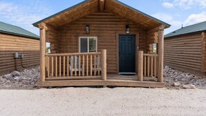 A wooden cabin with a porch, a door, and a window. - #9 Yellowstone Cabin w/ AC, Fire Pit & BBQ! (Saint Charles)