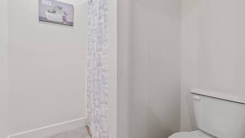 Une salle de bain avec des toilettes, un rideau de douche et une petite affiche accrochée au mur.