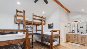 Una habitación con literas, un tocador de madera con espejo, y una pequeña foto en el marco colgada en la pared.
