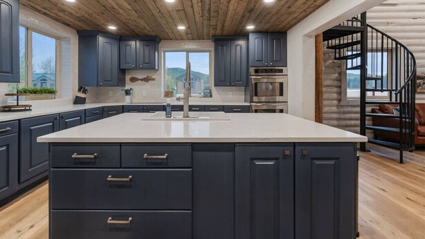 Una cocina moderna con armarios oscuros, una isla grande y un techo de madera.