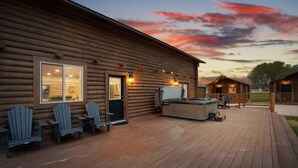 Una cabaña de madera con terraza, mobiliario exterior y un jacuzzi.
