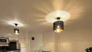 A modern living room with a sofa, a dining table, and a kitchen area in the background. - New apartment 5 minutes from Rouen's historic center - breathtaking view. (Rouen)