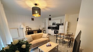A modern apartment with a living room, dining area, and kitchen. There is a sofa, a dining table with chairs, a coffee table, and a TV. - New apartment 5 minutes from Rouen's historic center - breathtaking view. (Rouen)