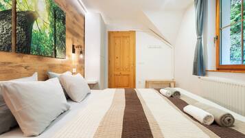A bedroom with a large bed, a wooden door, a window with curtains, and a wall-mounted light fixture.