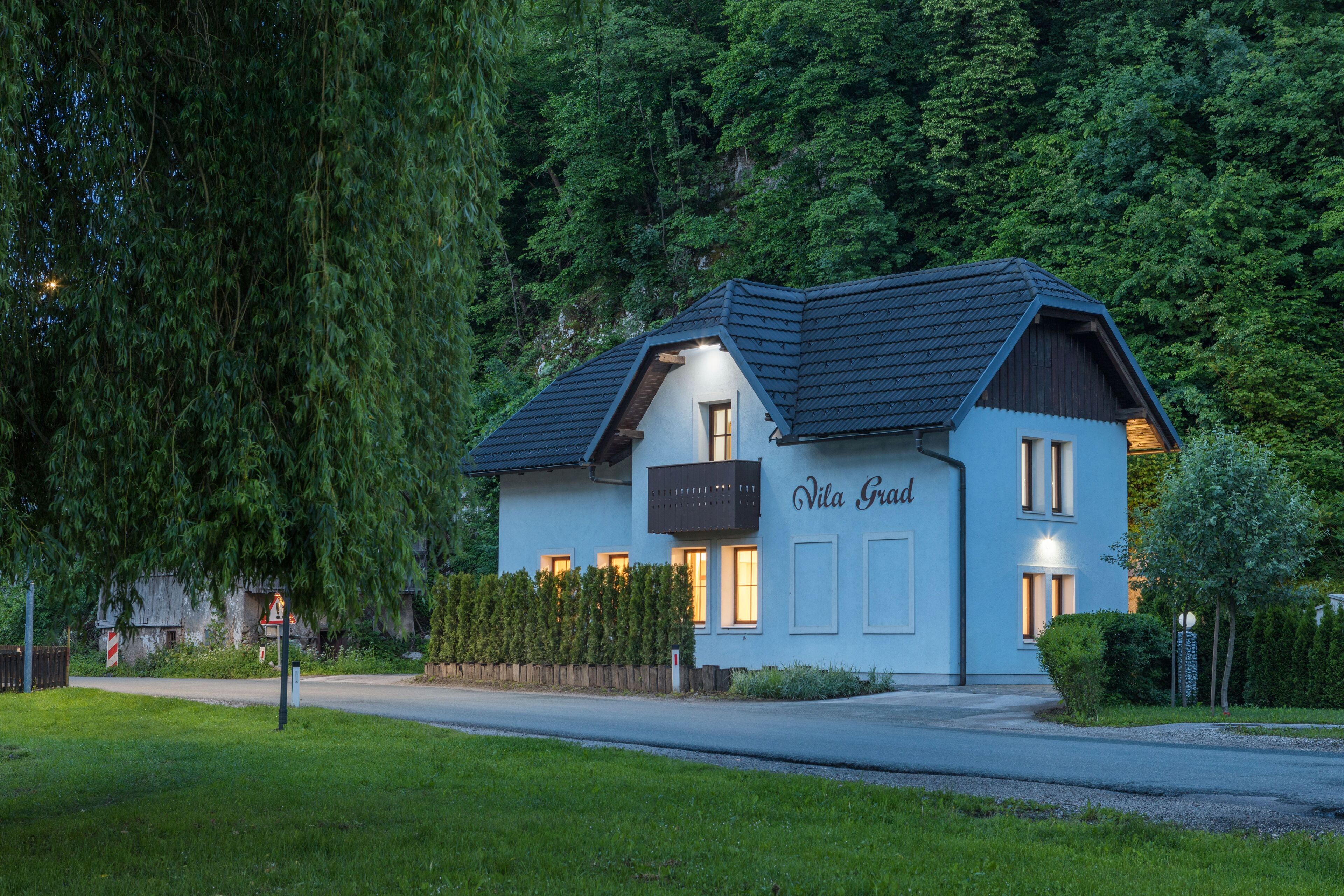 A two-story house with a sign reading "Villa Grand" and a well-maintained lawn.