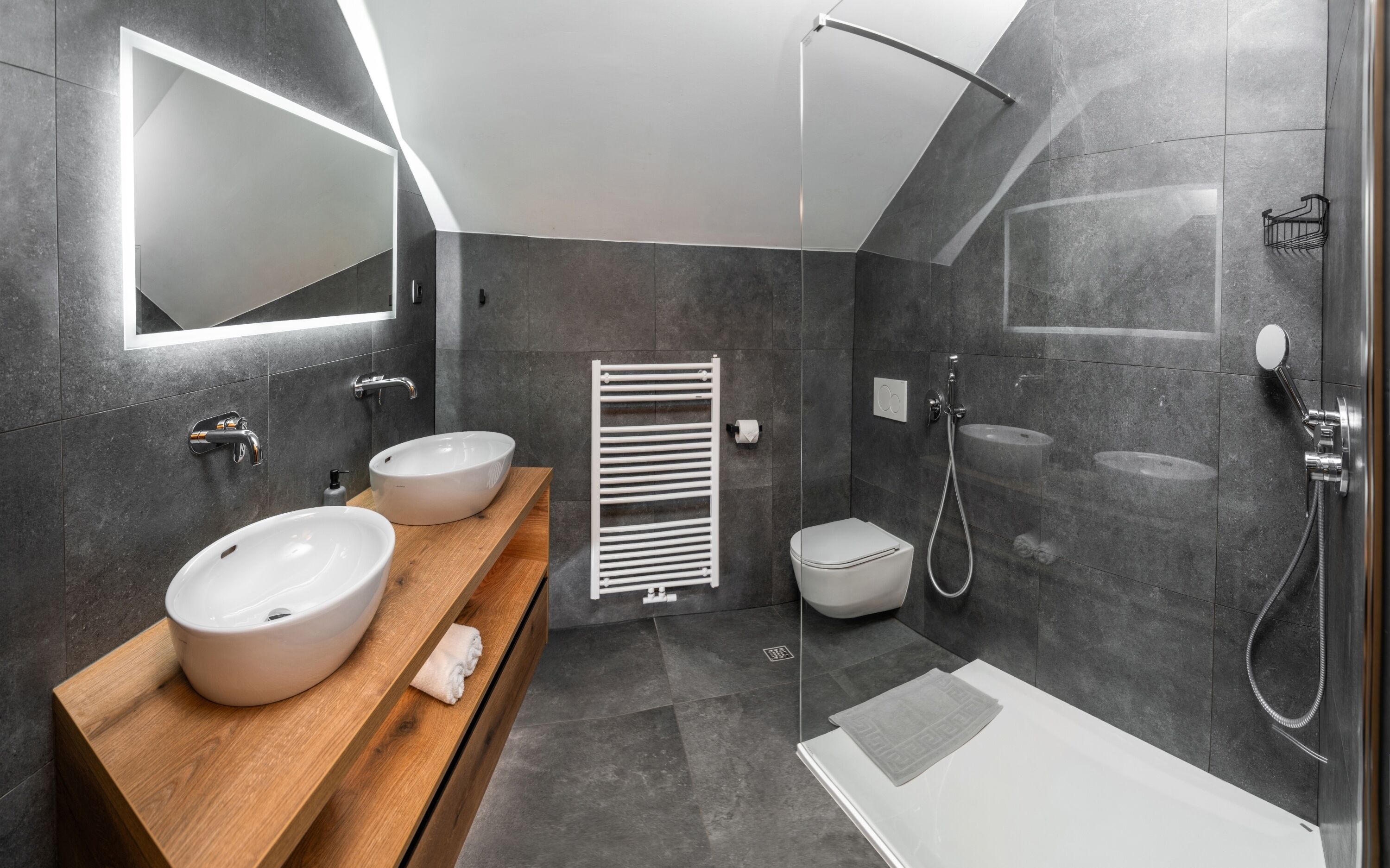 Un baño moderno con dos lavamanos, ducha e inodoro.
