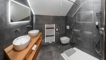 Un baño moderno con dos lavamanos, ducha e inodoro.