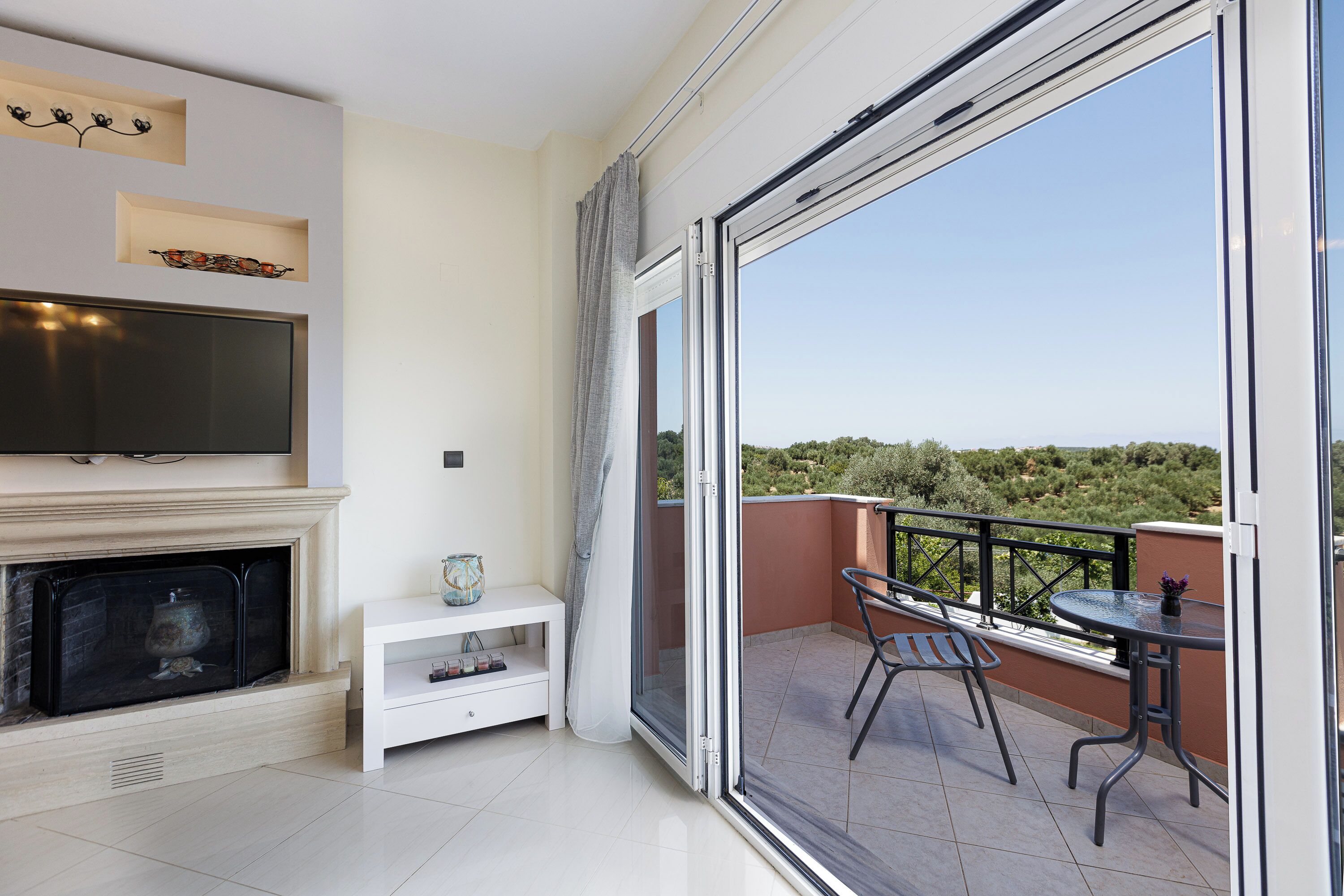 Un balcón con televisor, chimenea y mobiliario exterior.
