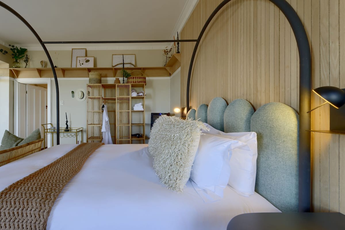 A neatly arranged bedroom with a large bed, a bedside table, a lamp, and a wardrobe.