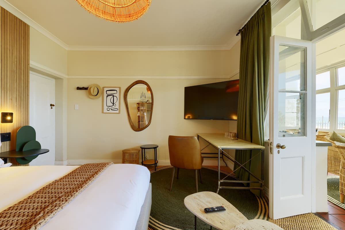 A hotel room with a bed, desk, chair, television, and a view of the outdoors.